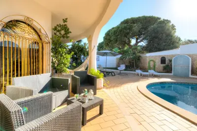 an outdoor patio with a swimming pool and chairs and a table at Villas2go2 V5 Vilamoura XXI in Vilamoura