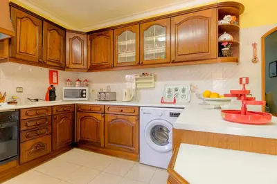 a kitchen with wooden cabinets and a washing machine at Villas2go2 V5 Vilamoura XXI in Vilamoura