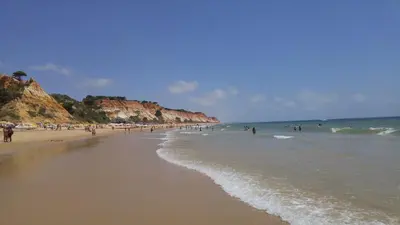 a beach with a bunch of people in the water at Olhos de Água Apartment Albufeira II in Albufeira