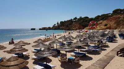 a beach with many umbrellas and chairs and people at Olhos de Água Apartment Albufeira II in Albufeira