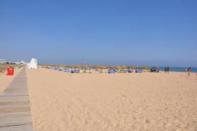 a sandy beach with a pier and a group of buildings at Marina Vilamoura Penthouse Aquamar 606 in Vilamoura