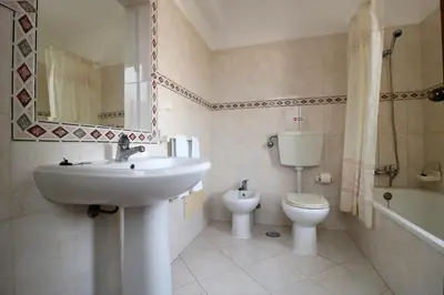 a white bathroom with a sink and a toilet at Villa Gonçalves in Albufeira