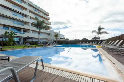 a large swimming pool with chairs and a building at Marina Vilamoura - Aquamar 215 - VilamouraSun in Vilamoura
