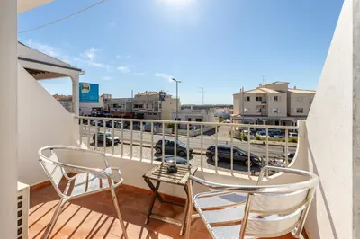 a balcony with chairs and a table and a view of a city at Guest House Oliveira in Boliqueime