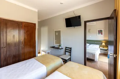 a hotel room with two beds and a mirror at Guest House Oliveira in Boliqueime