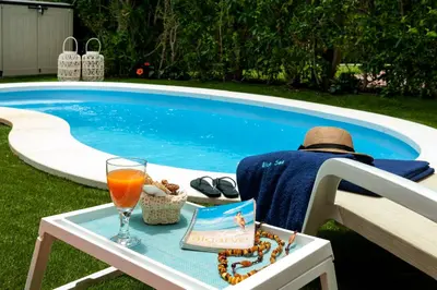 a man sitting in a chair next to a table with a drink at Vila dos Lírios - Blue Sea in Albufeira