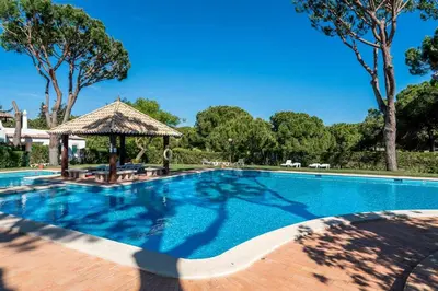 a large swimming pool with a gazebo and trees at Solar do Golfe apt 101 - By Vilamoura Sun in Vilamoura