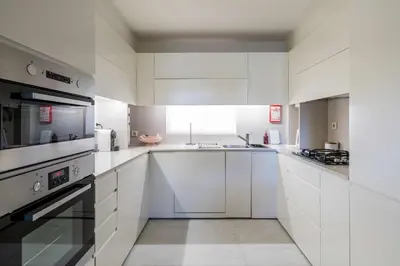a white kitchen with white cabinets and appliances at Solar do Golfe apt 101 - By Vilamoura Sun in Vilamoura