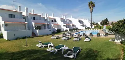 a row of white buildings with lawn chairs and a swimming pool at Oura Parque Apartamentos Turisticos in Albufeira