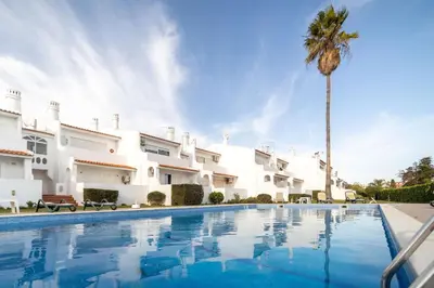 a villa with a swimming pool and a palm tree at Oura Parque Apartamentos Turisticos in Albufeira