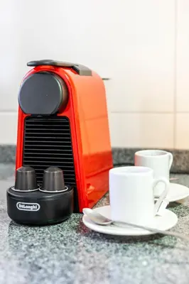 an orange toaster sitting next to a white coffee cup at Vilamoura Garden House - Golf & Beach in Vilamoura