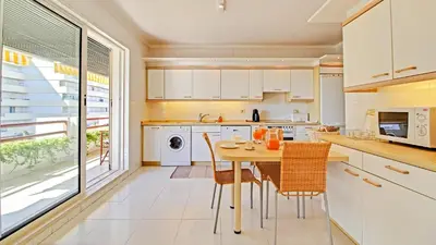 a kitchen with white cabinets and a table and chairs at Marina Sagres Apartment in Vilamoura