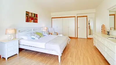 a bedroom with a white bed and a wooden floor at Marina Sagres Apartment in Vilamoura