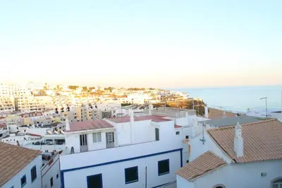 a view of a town with houses and the ocean at Casa do Sol in Albufeira