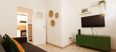 a living room with a couch and a television on a wall at Casa do Sol in Albufeira
