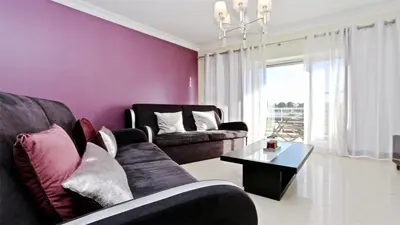 a living room with purple walls and a couch and a table at Moura Praia - Clever Details in Vilamoura