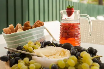 a plate of food with grapes and a strawberry on top at Vila dos Girassóis - BlueSea in Albufeira