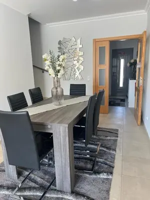 a dining room table with black chairs and a vase of flowers at Vila Branca in Albufeira