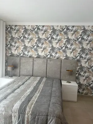 a bedroom with a large bed with a floral wallpaper at Vila Branca in Albufeira