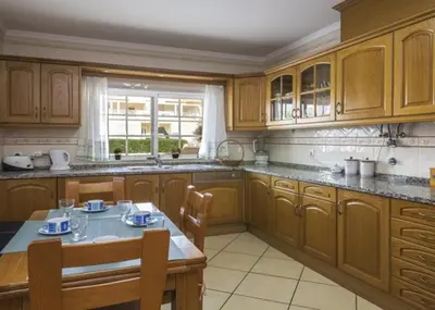 a kitchen with wooden cabinets and a table with chairs at Villa Coelho - By Algarkasa in Albufeira