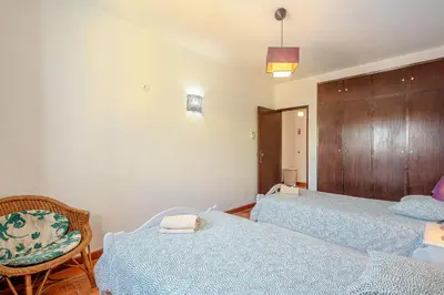 a bedroom with two twin beds and a chair at Villa Amendoeira-POOL HEATED - By Algarkasa in Guia