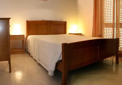 a bedroom with a large wooden bed with white sheets at Villas King's in Albufeira