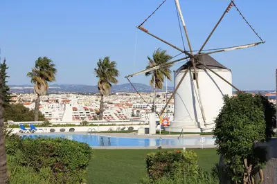 a windmill and a pool with a city in the background at Windmill Hill in Albufeira