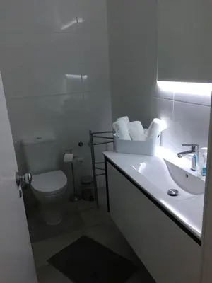 a white bathroom with a toilet and a sink at Charmosous Flat in Albufeira