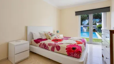 a bedroom with a bed and a window and a pool at Villa Girassol in Vilamoura