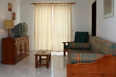a living room with a couch and a tv at Apartamentos King's in Quarteira