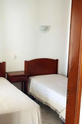 a hotel room with two beds and a nightstand and a bed sidx sidx sidx at Apartamentos King's in Quarteira
