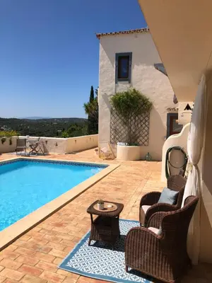 a swimming pool with two chairs and a table next to a house at Felicidade in Loulé