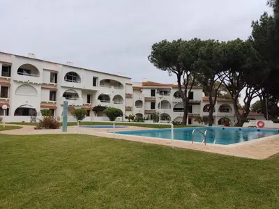 a hotel with a swimming pool in front of a building at Vieira apartment 1 in Quarteira