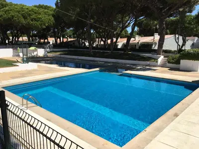 a large blue swimming pool next to a fence at Estúdio tranquilo praia da Falésia in Albufeira