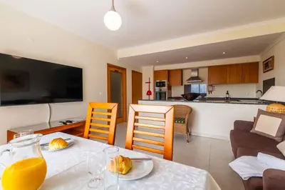 a kitchen and a living room with a table with orange juice at Vista das Ondas by Algarneto in Albufeira