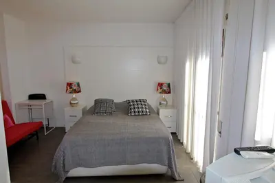 a white bedroom with a bed and a red chair at Marina Parque 83 - Clever Details in Vilamoura