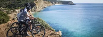 a man riding a bike on a cliff overlooking the ocean at Marina Vilamoura - Aquamar 401- Modern Apartment in Vilamoura