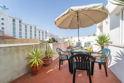 a patio with a table and chairs and an umbrella at Lena`s Beach House by HelloVacations in Albufeira
