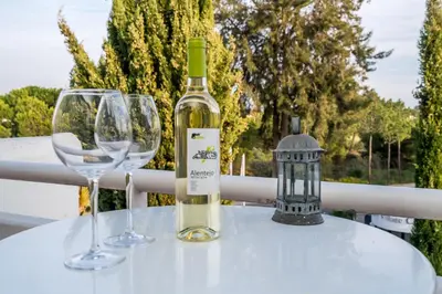 a bottle of wine and two wine glasses on a table at BmyGuest - Quinta do Lago Lounge Apartment in Almancil