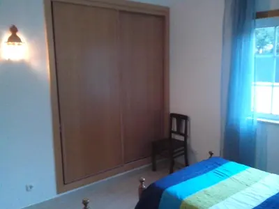 a bedroom with a large wooden closet next to a bed at Albufeira 2 bedroom apartment 5 min from Falesia beach and close to center B in Albufeira