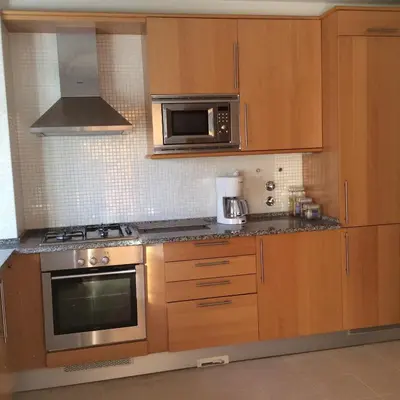 a kitchen with stainless steel appliances and wooden cabinets at Corcovada in Albufeira