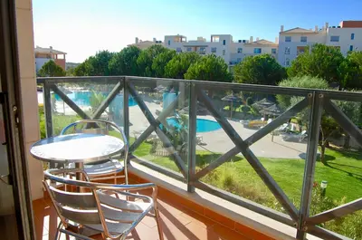 a balcony with a table and chairs and a view of a pool at Corcovada in Albufeira