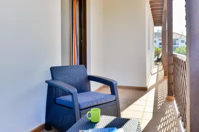 a blue chair on a balcony with a green cup at Falesia Beach A in Roja- Pé
