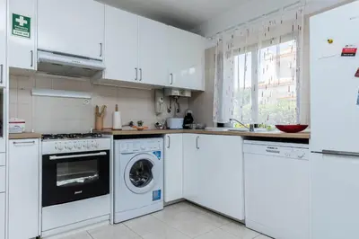 a kitchen with white cabinets and a washer and dryer at Akisol Olhos de Agua Pine II in Albufeira