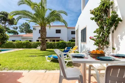 a patio with a table and chairs and a yard at Akisol Olhos de Agua Pine II in Albufeira
