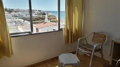 a chair sitting in a room with a window at Vivenda João Damas in Albufeira