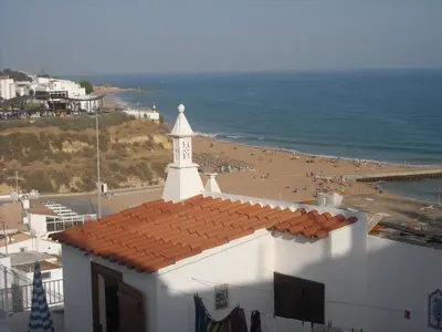 a white building with a red roof and a beach at Vivenda João Damas in Albufeira