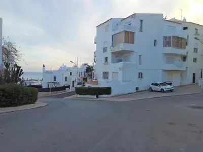 a white building with a car parked next to a street at Apartamento de Praia - Albufeira in Albufeira