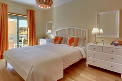 a white bedroom with a bed and a window at Marina Bay Residence in Albufeira