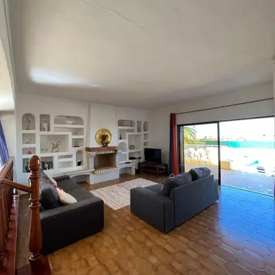 a living room with two couches and a sliding glass door at Villa Paraiso - 4 Bedrooms and pool in Albufeira